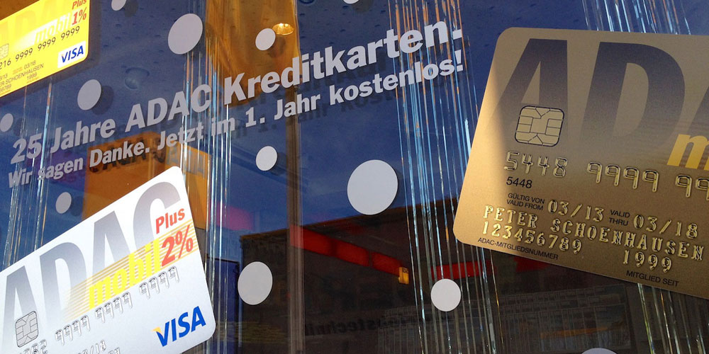 Schaufensterdekoration und Fensterbeschriftung. Hier Kreditkarten Digital gedruckt und auf die Scheibe montiert. Dazu silberfarbene Punkte und im Hintergrund silberfarbene Fäden.