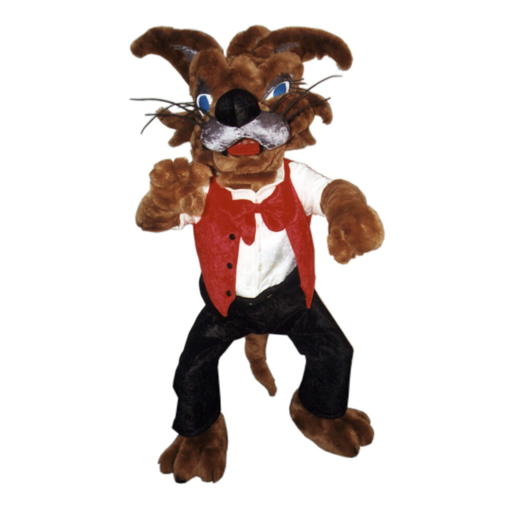 Maskottchen für einen Freizeitpark. Wolf aus Kunstfell trägt eine schwarze Hose ein weißes Hemd und eine rote Weste mit roter Fliege.