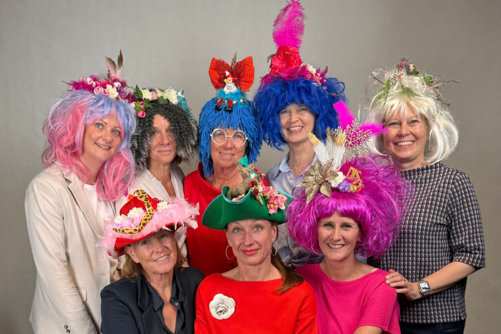 8 Frauen mit DIY gestalteten Hüten und Perücken beim Workshop