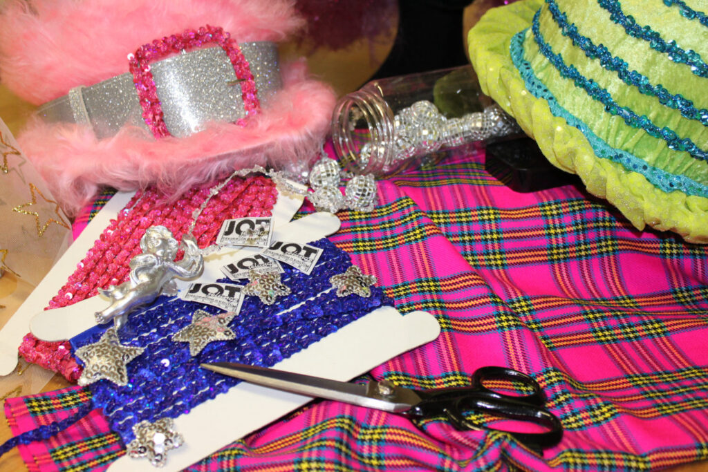 Einen Tisch mit Stoffen, Bändern und Accessoires für die Gestaltung von Kopfbedeckung, Perücken und Kostüme